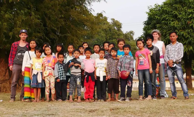 Gruppenfoto von Kindern und Jugendlichen des Kinderheims im Freien vor Bäumen.