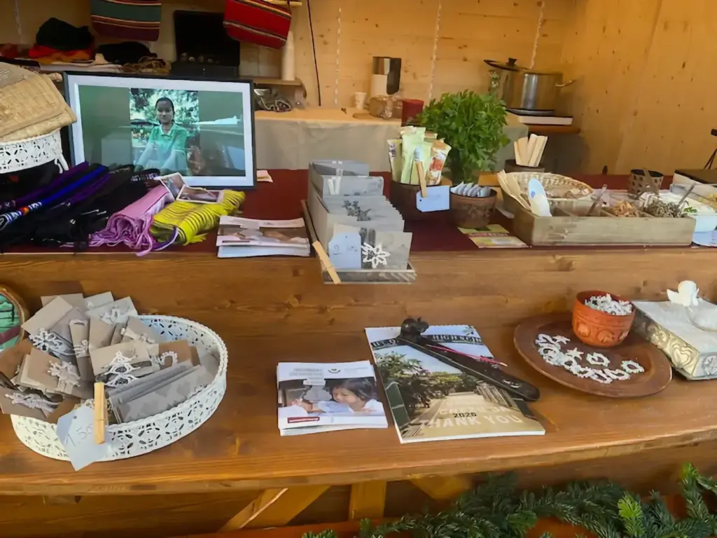 Geschenkideen, Flyer und ein Bildschirm mit Fotos auf dem Tresen des Standes.