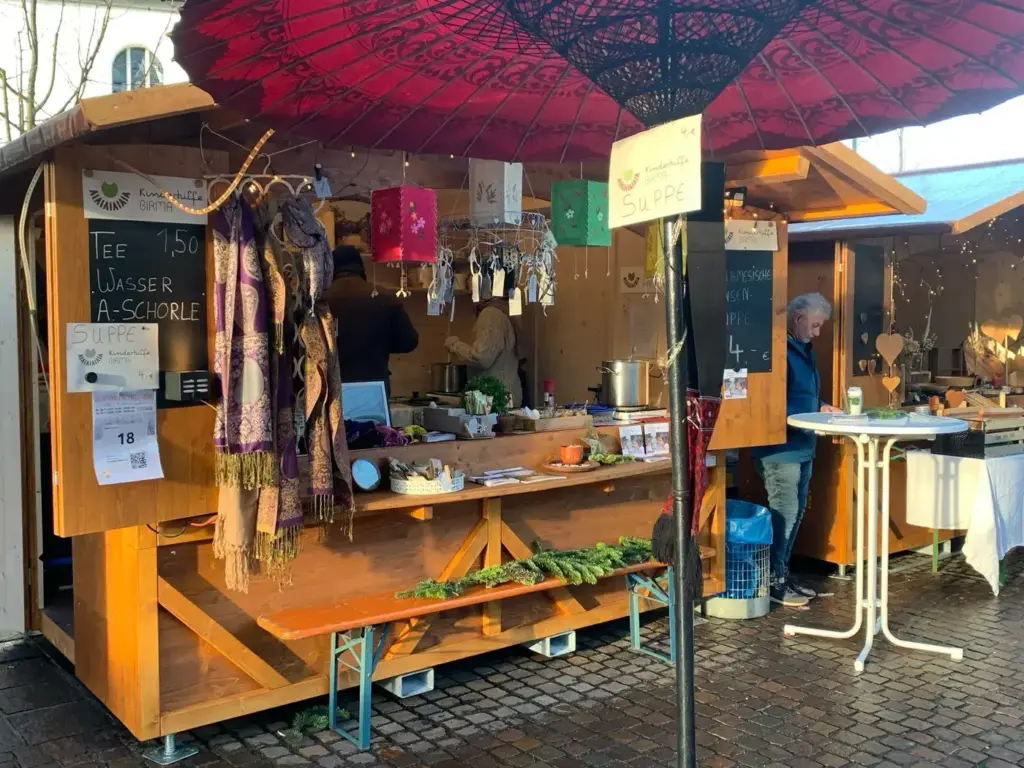 Der Weihnachtsmarktstand des Vereins in Kressbronn mit rotem Schirm.