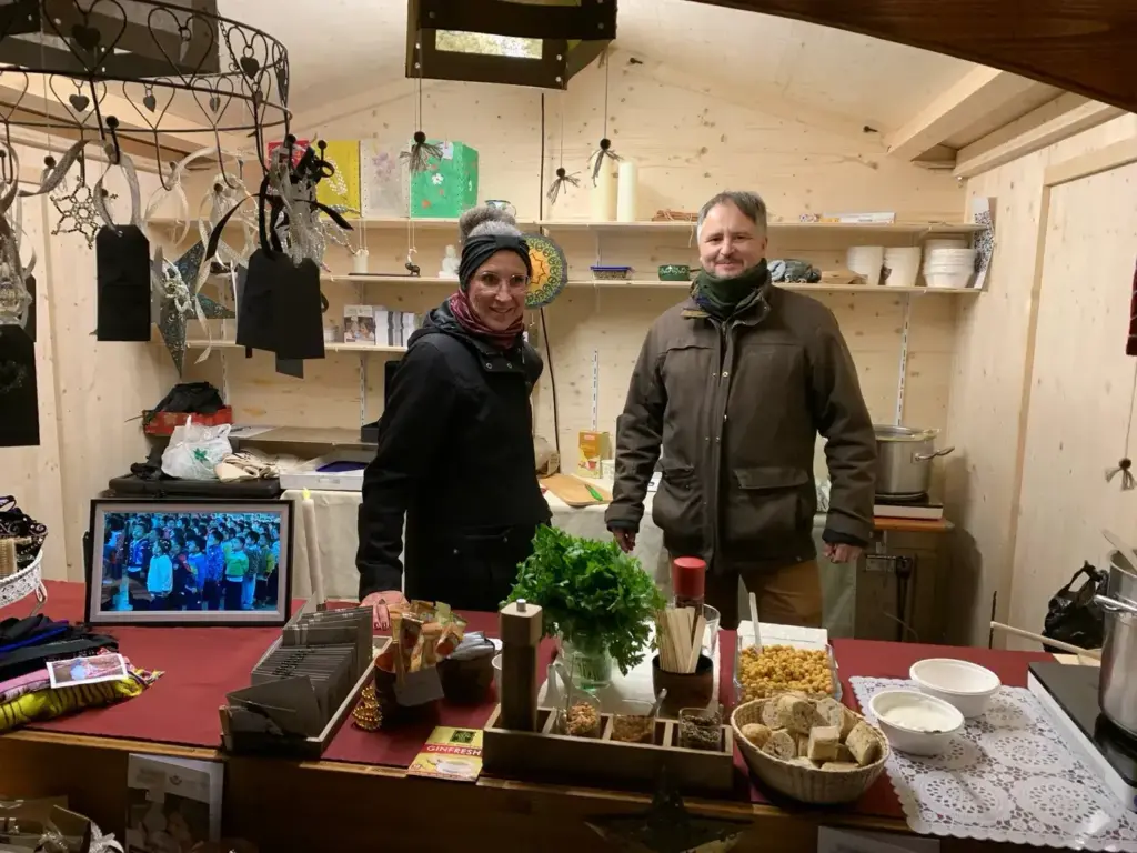Zwei Vereinsmitglieder stehen hinter dem Tresen der Weihnachtsmarkthütte.