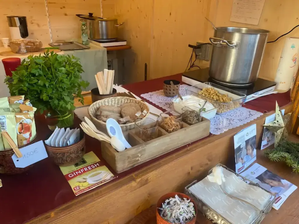 Tresen mit Suppentopf, Kräutern und Infomaterial am Weihnachtsmarktstand.