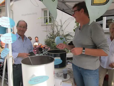 Zwei Männer schöpfen am Herbstmarkt 2011 Suppe aus großen Töpfen.
