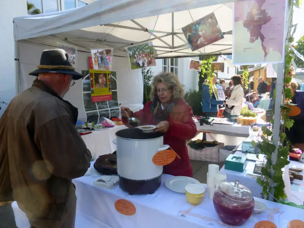 Ein Besucher mit Hut lässt sich am Herbstmarktstand 2013 Suppe aus einem großen Topf schöpfen.