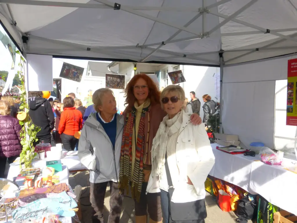 Drei Frauen stehen lächelnd im Pavillon des Vereinsstands auf dem Herbstmarkt 2013.
