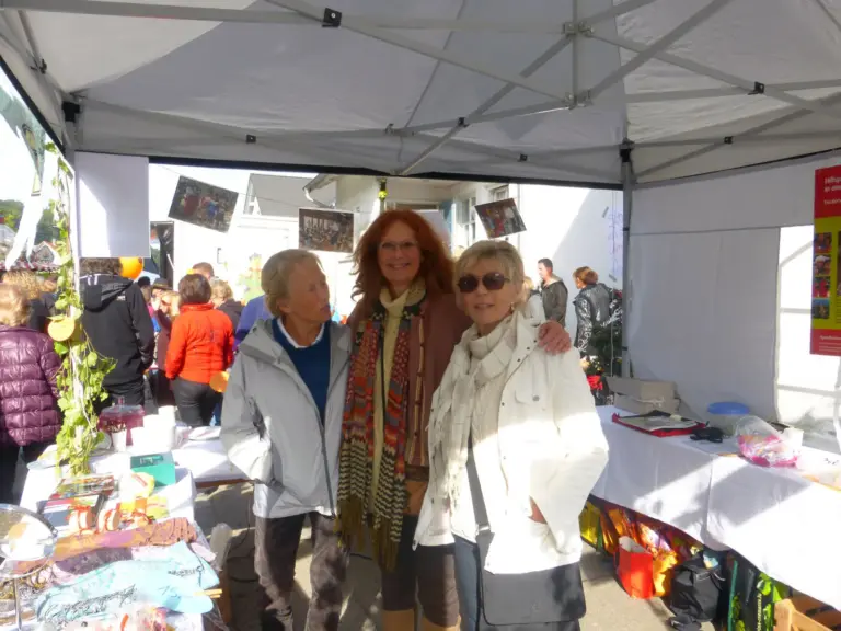 Drei Frauen stehen lächelnd im Pavillon des Vereinsstands auf dem Herbstmarkt 2013.
