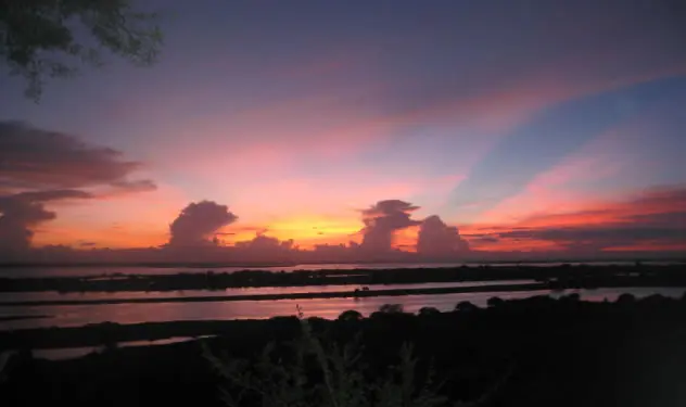 Sonnenuntergang mit rot leuchtenden Wolken über einer weiten Landschaft in Myanmar.