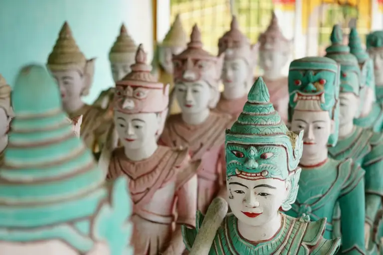 Reihen bemalter Figuren in einem buddhistischen Tempel.