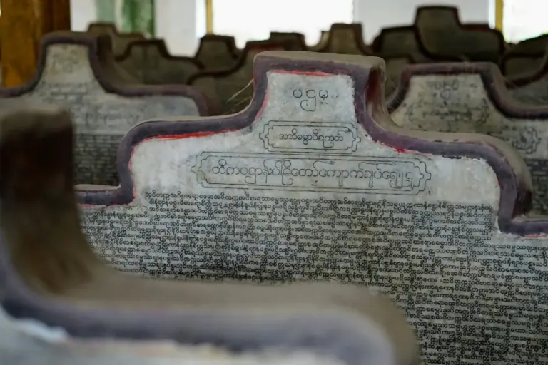 Beschriftete Steintafeln mit birmanischer Schrift in einer Pagode.