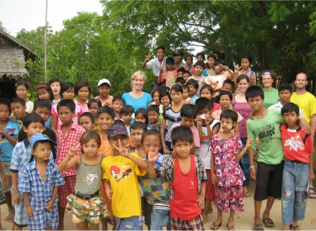 Viele Kinder und einige Besucher stehen dicht gedrängt für ein Gruppenfoto im Freien.