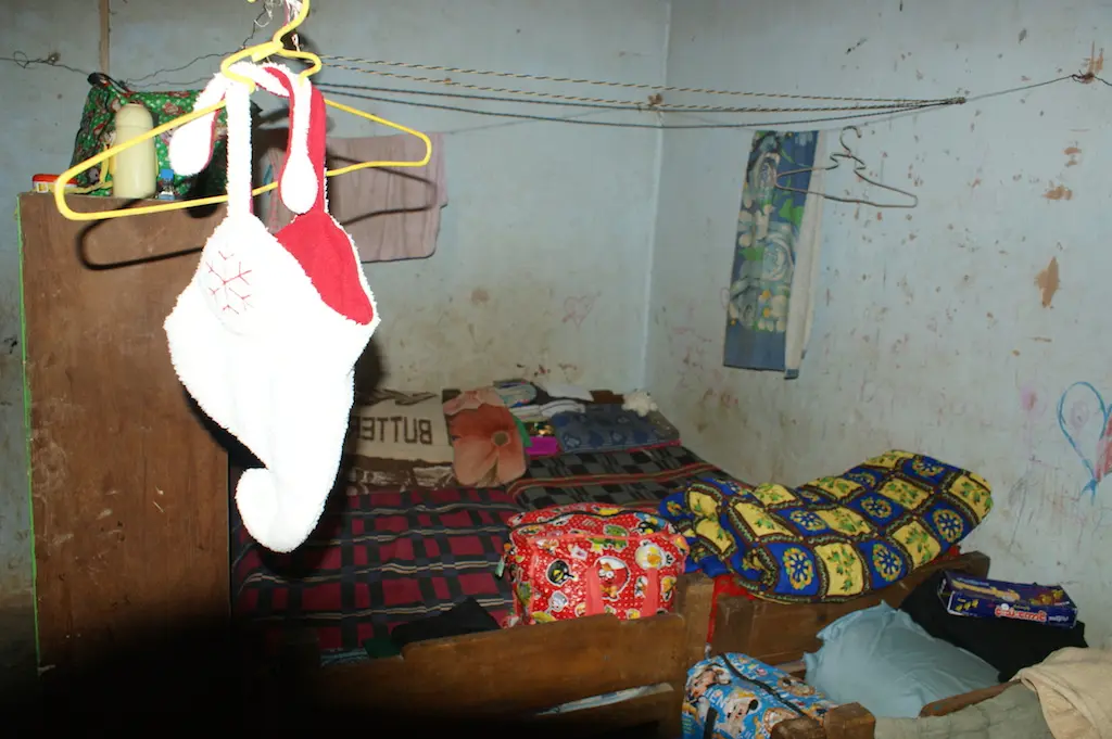 Schlafplatz im Kinderheim mit bunten Decken, an der Wand hängt ein Weihnachtsstrumpf.