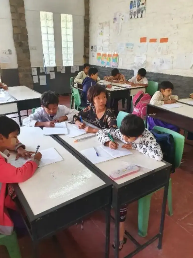 Kinder arbeiten an Tischen in einem hellen Klassenraum der Light of Love School.