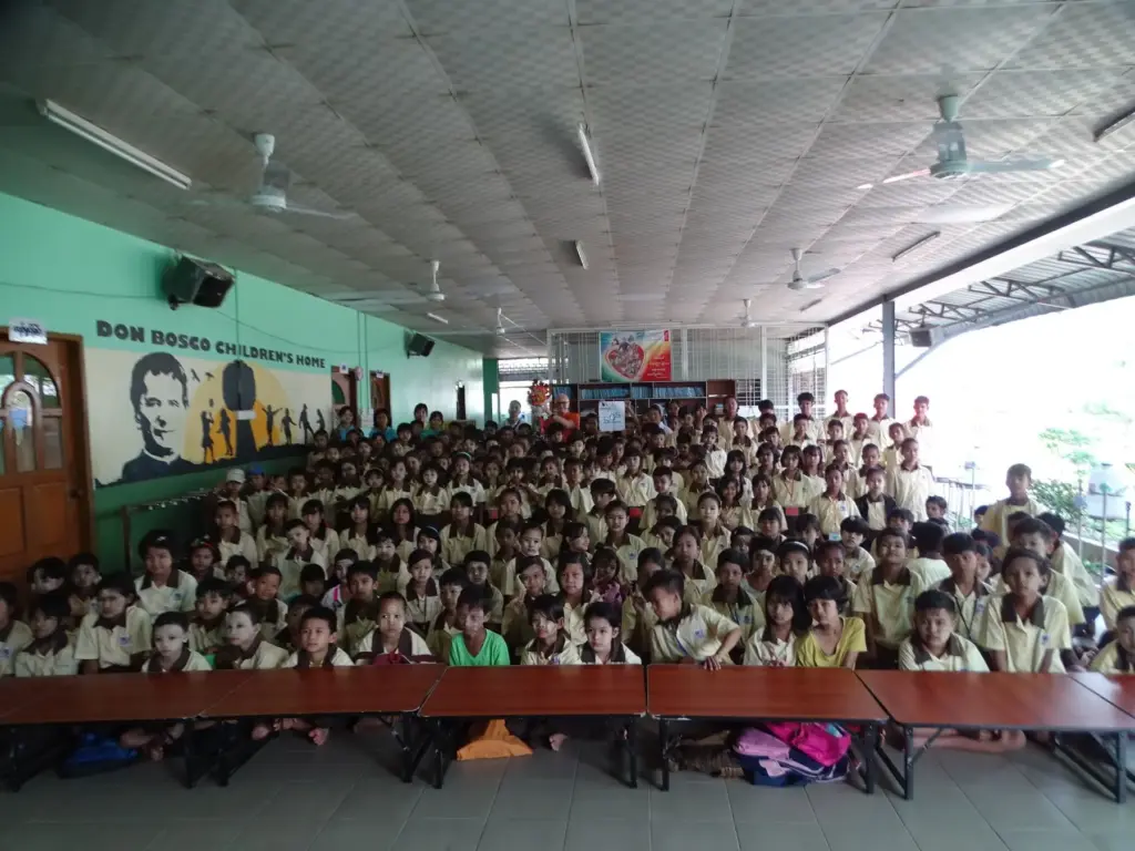 Die gesamte Schülerschaft sitzt in der großen Halle der Light of Love School.