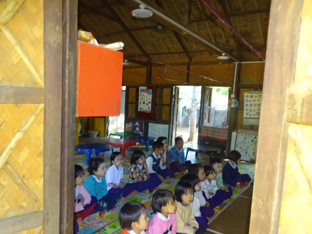 Kleine Kinder sitzen im Kindergarten auf dem Boden.