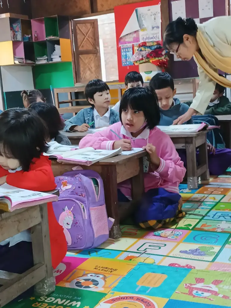 Mädchen schreiben an ihren Tischen im Kindergarten der Schule.