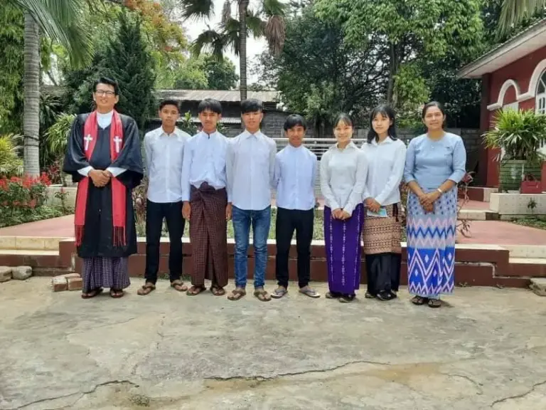 Die getauften Jugendlichen stehen mit dem Pastor für ein Gruppenfoto.