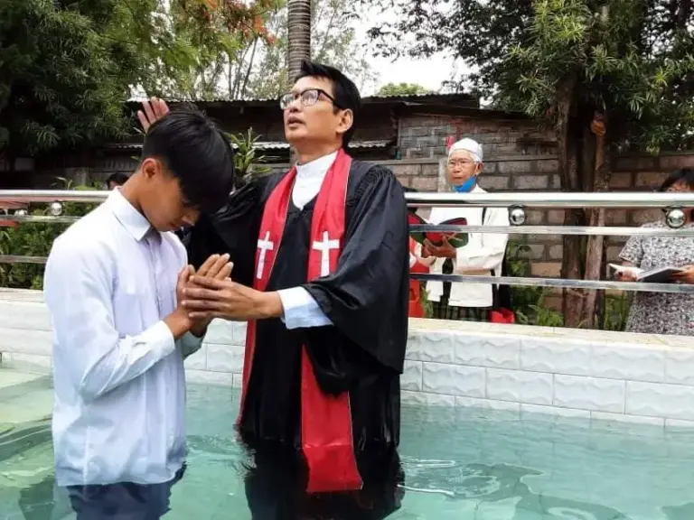 Taufe eines Jugendlichen im Becken, der Pastor hält seine Hände.