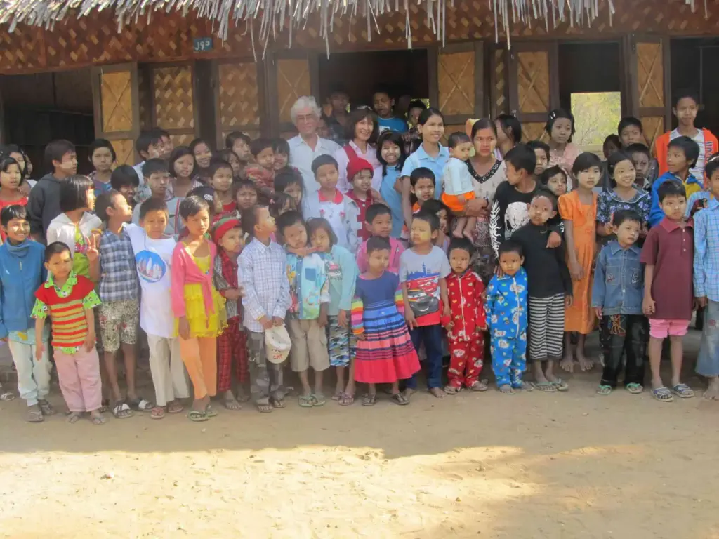 Große Gruppe von Kindern vor dem strohgedeckten Schulgebäude in Yenangyaung.
